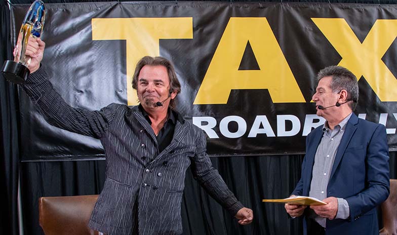 Jonathan Cain of Journey, triumphantly holding up his Lifetime Achievement award prior to doing his Keynote Interview with TAXI’s Michael Laskow.